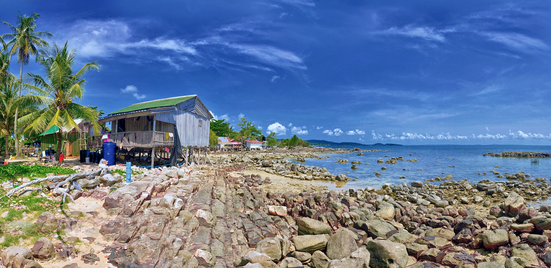 A wooden stilt house above a rocky shoreline on the coast at Kep