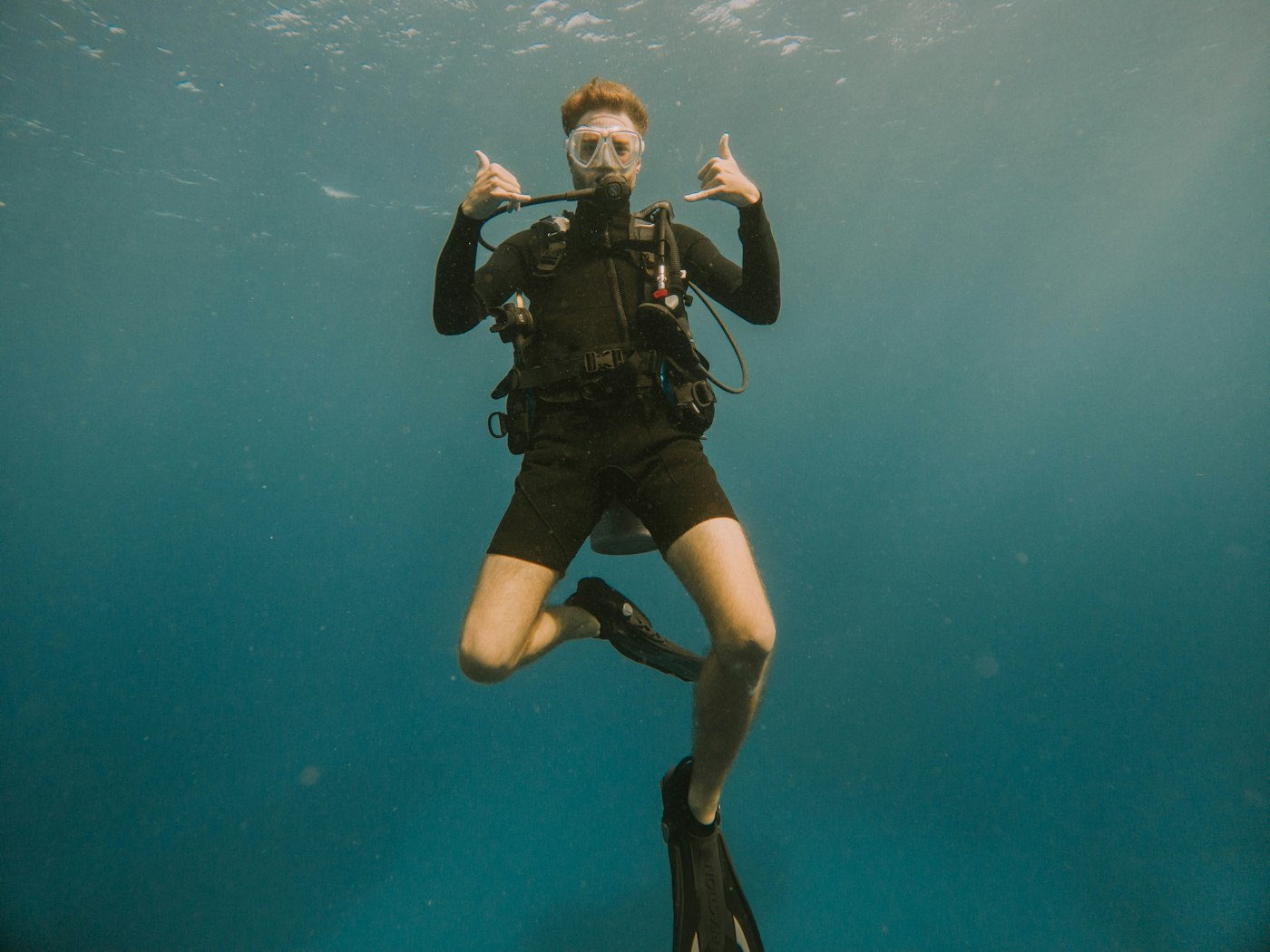 A diver in a wetsuit entering the water off East End, Grand Cayman