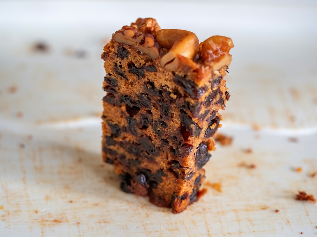 A thick dense dark cake standing on a plate