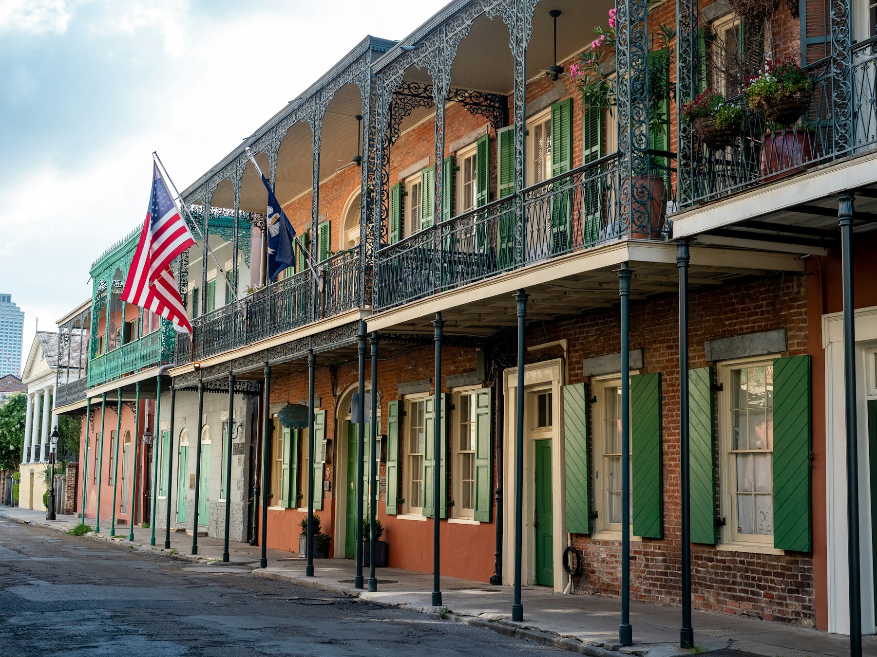 A row of French Quarter buildings with iron balconies and flags in New Orleans