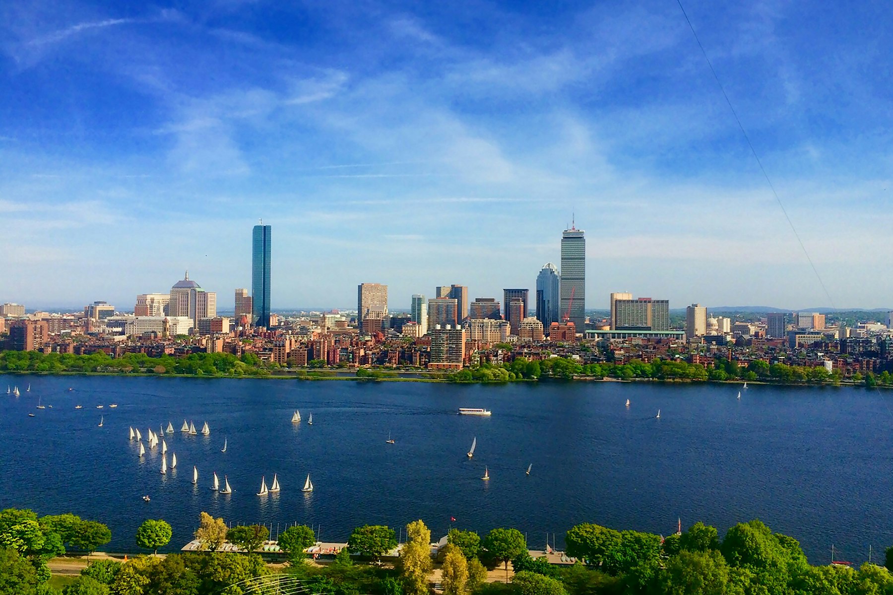 The Boston skyline seen across the Charles River with sailboats on the water on a clear day