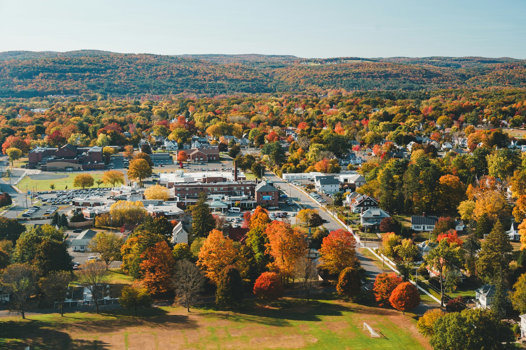 An aerial view of a small Berkshires town surrounded by hills in full autumn colour