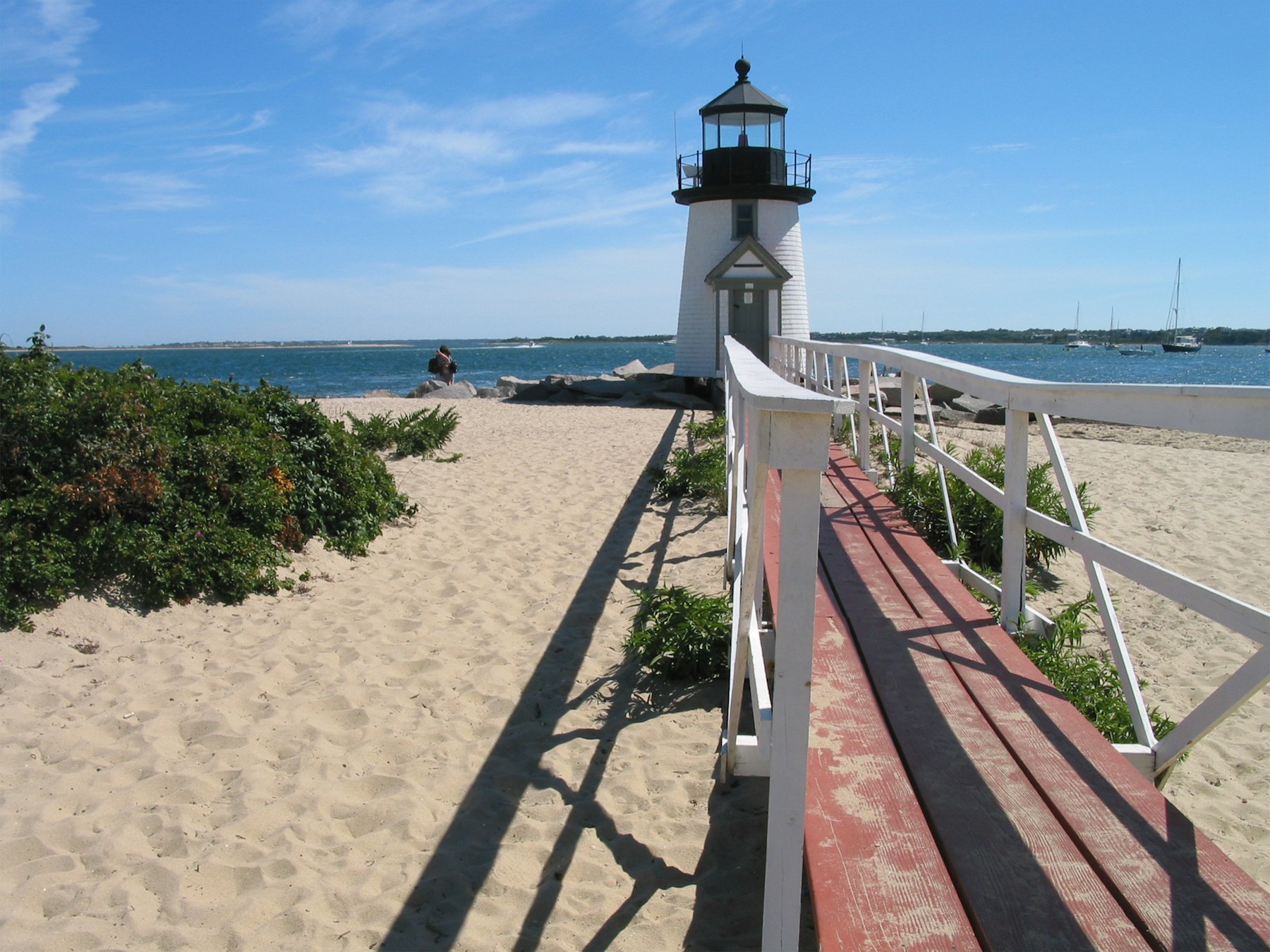 Brant Point Light on Nantucket with a wooden boardwalk leading across the sand toward it