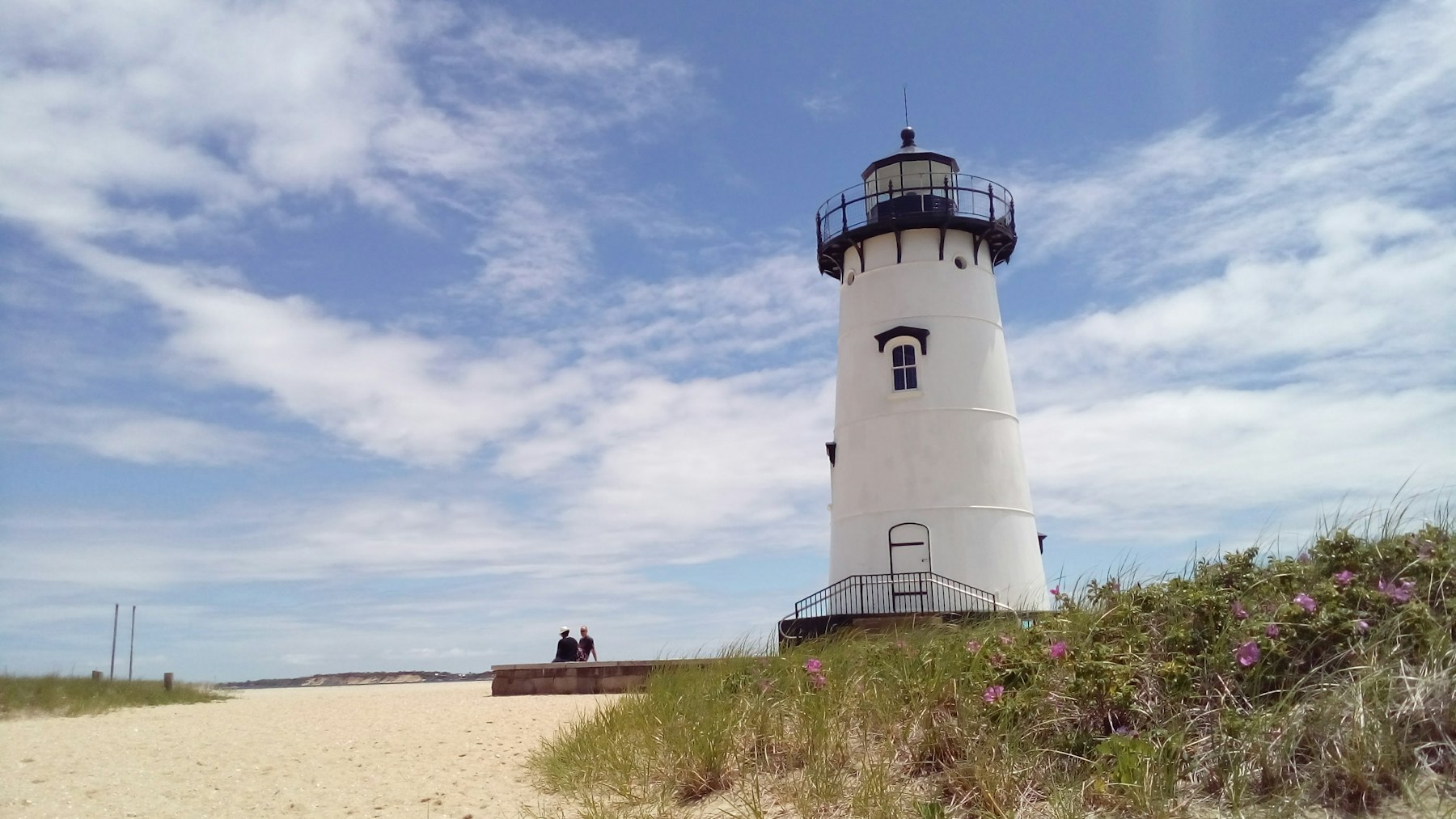 The white Edgartown Harbor Light standing on sand on Martha's Vineyard under a blue sky