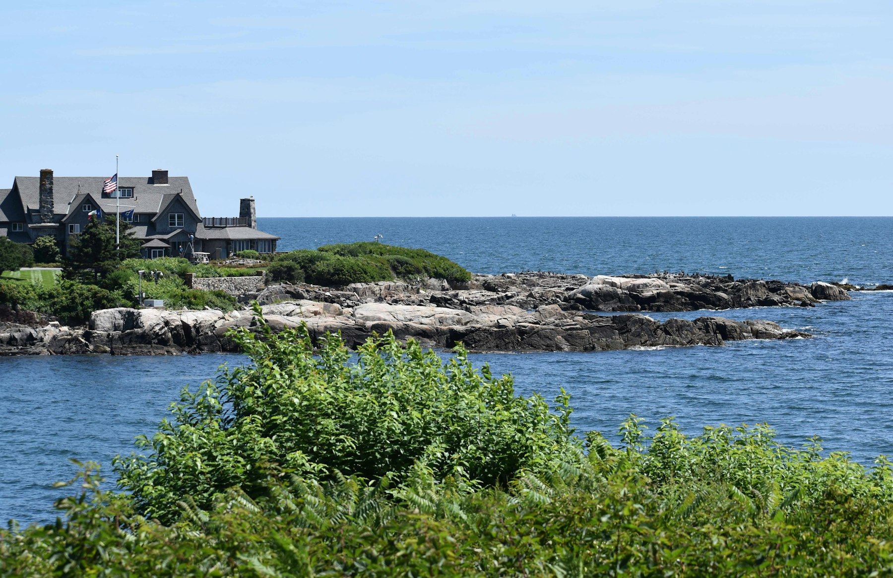 A shingled house on a rocky point above the ocean at Kennebunkport Maine