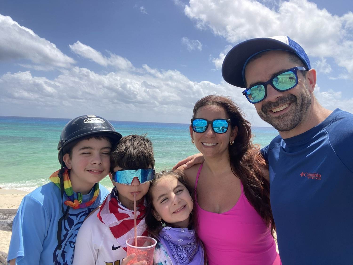 Nicole Adam and the three children on a Cozumel beach with turquoise Caribbean water behind them