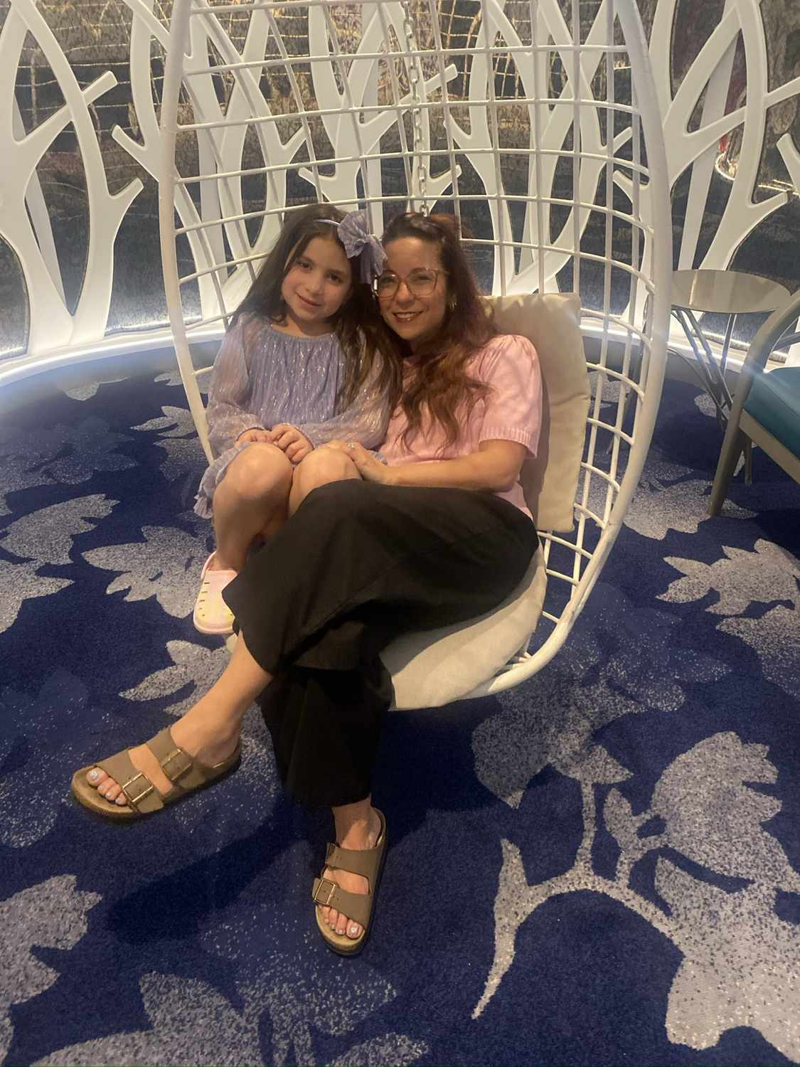 Nicole and her daughter Avilene sitting together in a hanging chair at a hotel on Isla Mujeres