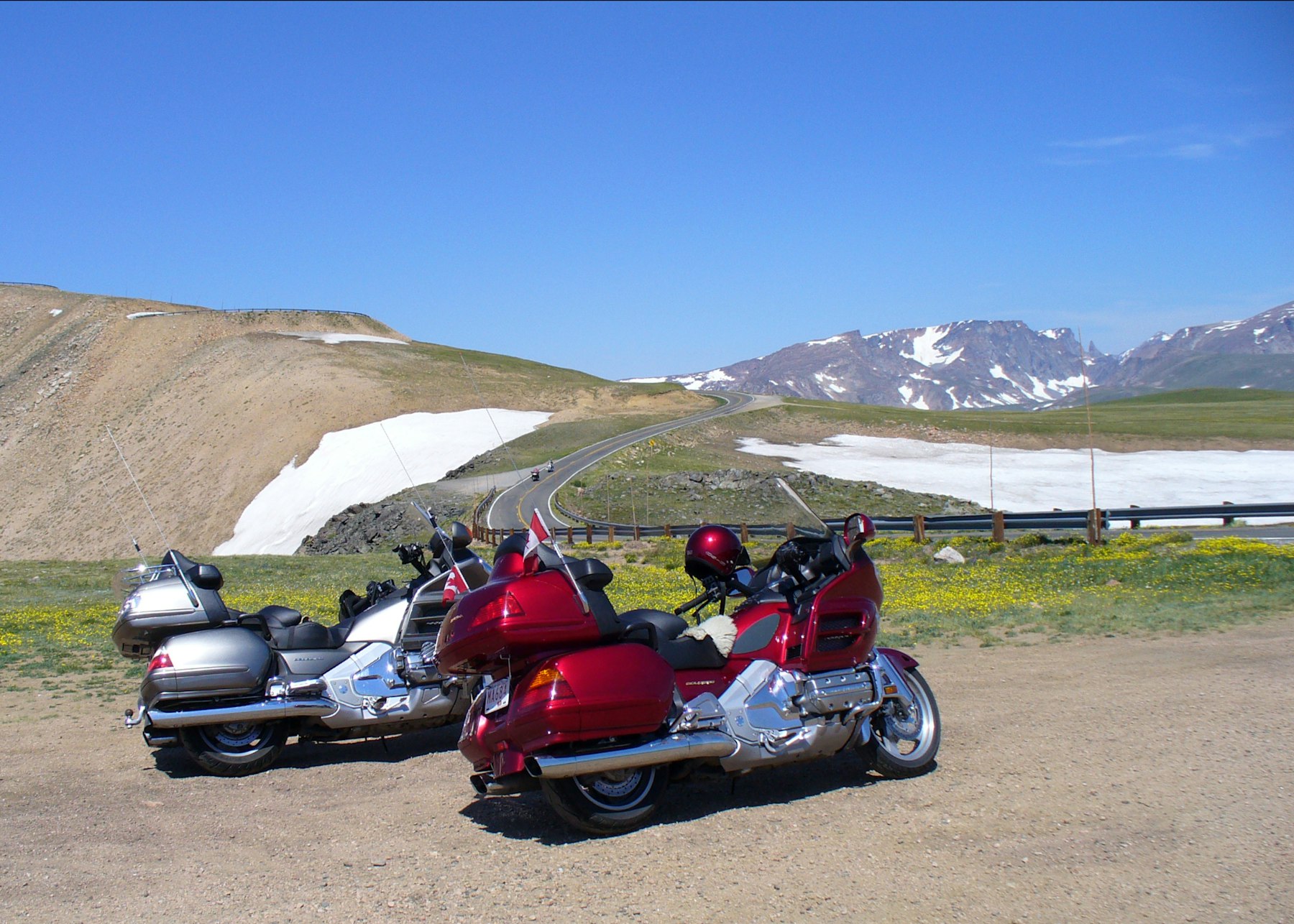 Motorcycles parked beside deep snow banks on a high alpine pass in Montana