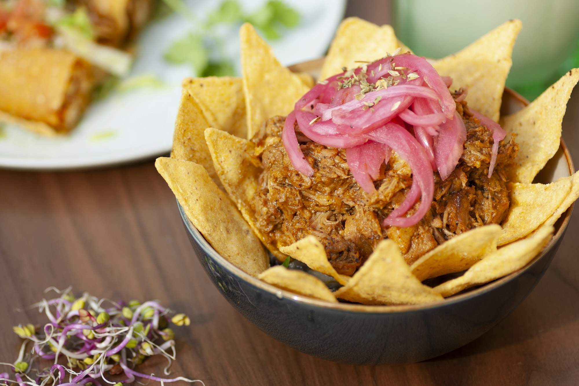 A bowl of cochinita pibil topped with pink pickled red onion