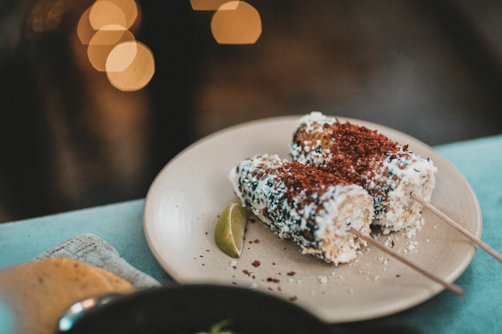An ear of Mexican street corn on a stick covered in mayonnaise cheese and chili powder