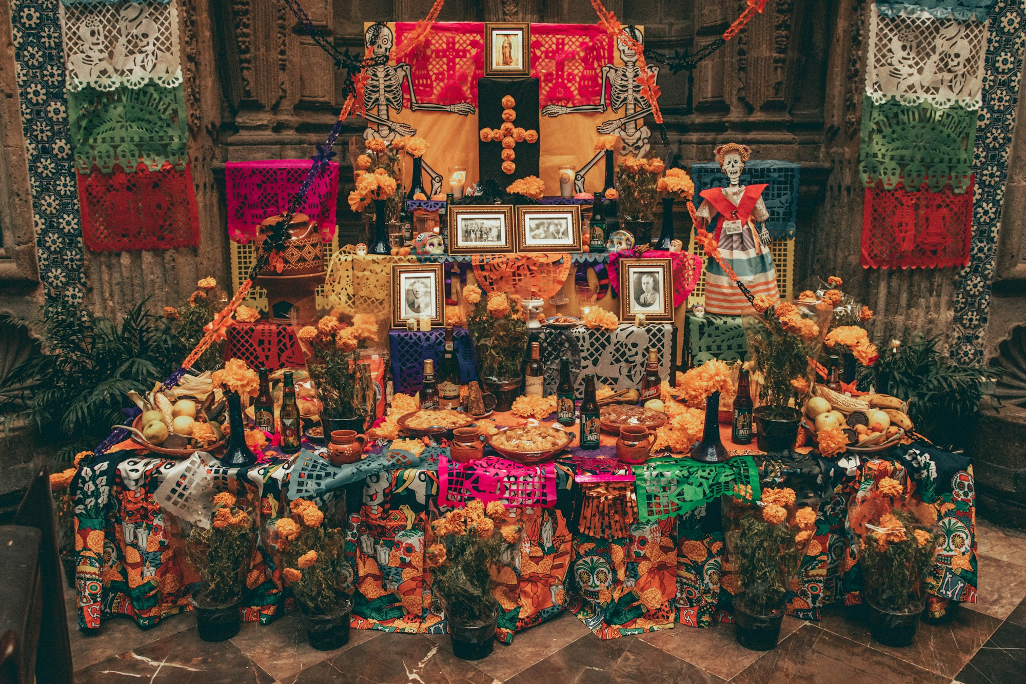 A Day of the Dead ofrenda altar covered in marigolds candles photographs and food offerings