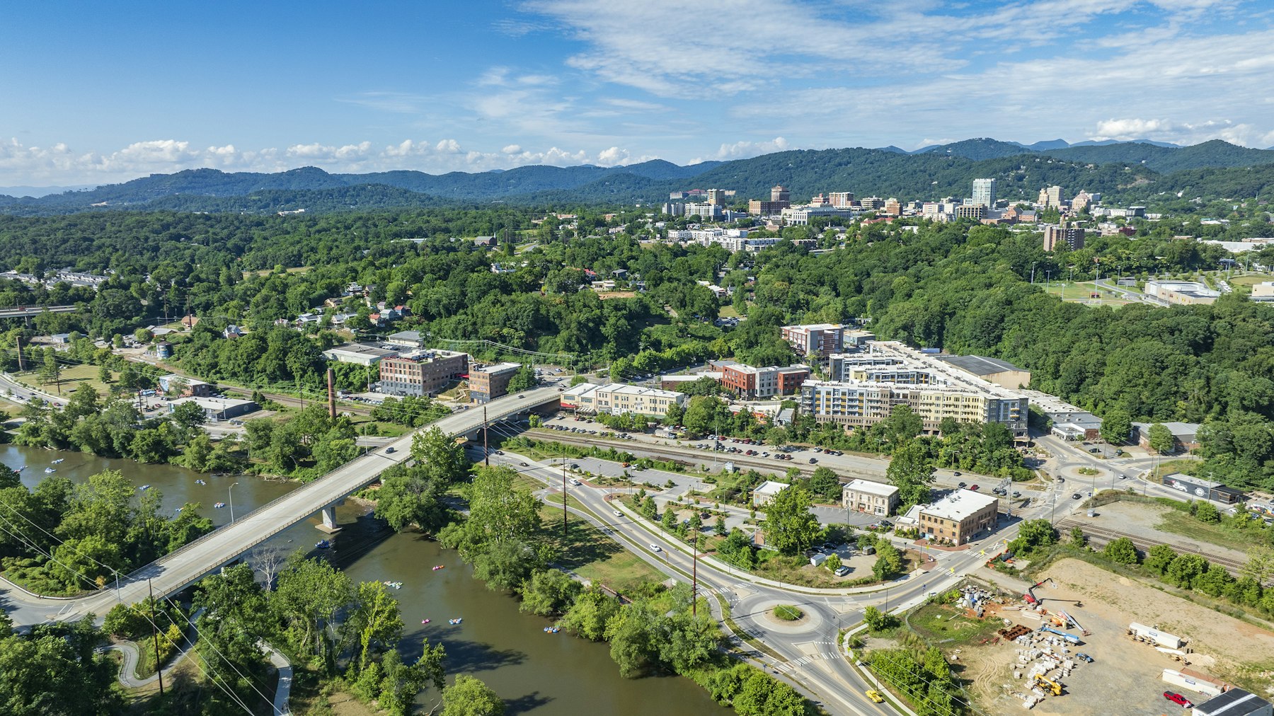 An aerial view of Asheville North Carolina with the French Broad River running through it and mountains behind