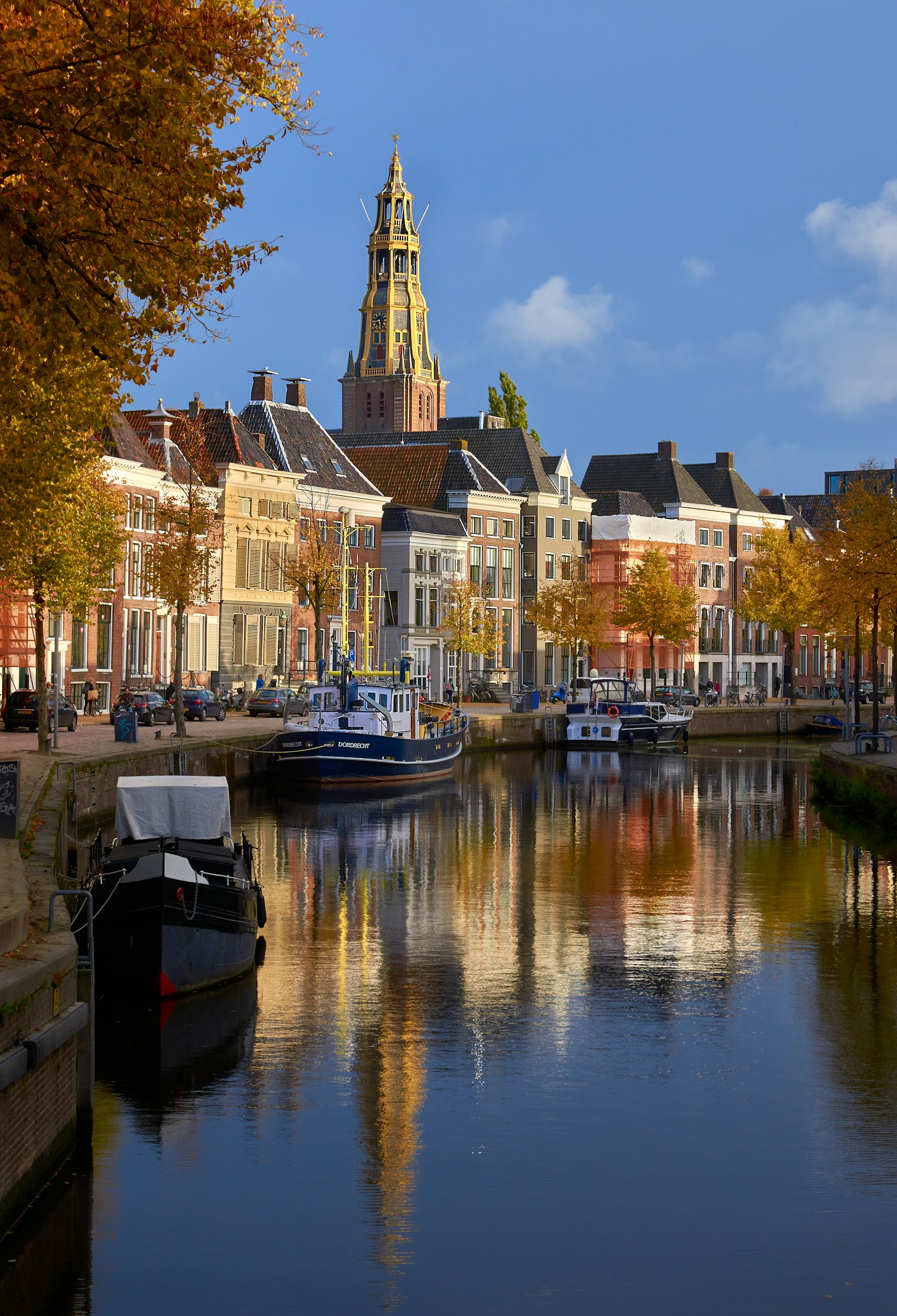 Gabled brick houses and moored boats along a still canal in Delft
