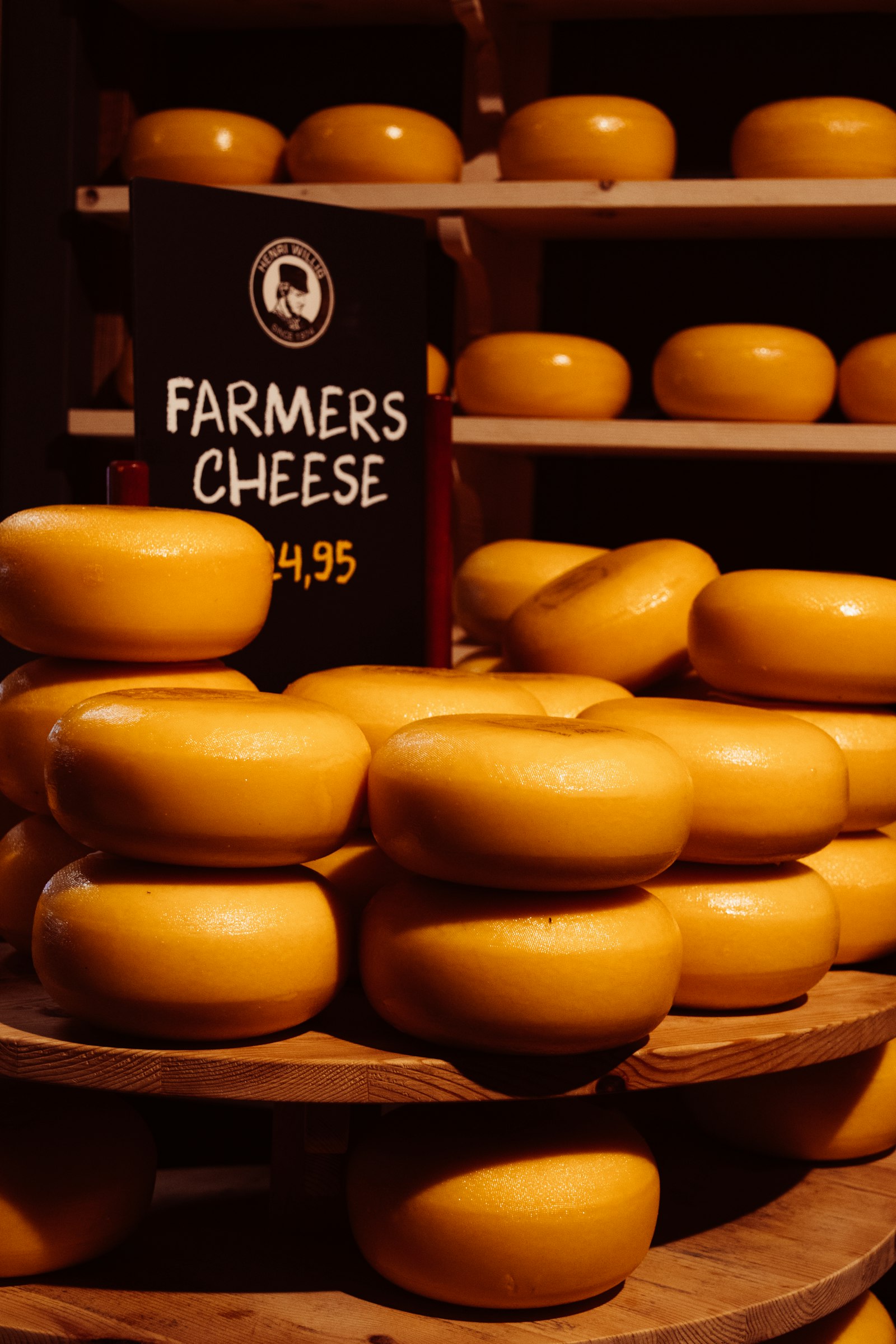 Stacked wheels of orange Dutch farmers cheese on a market stall