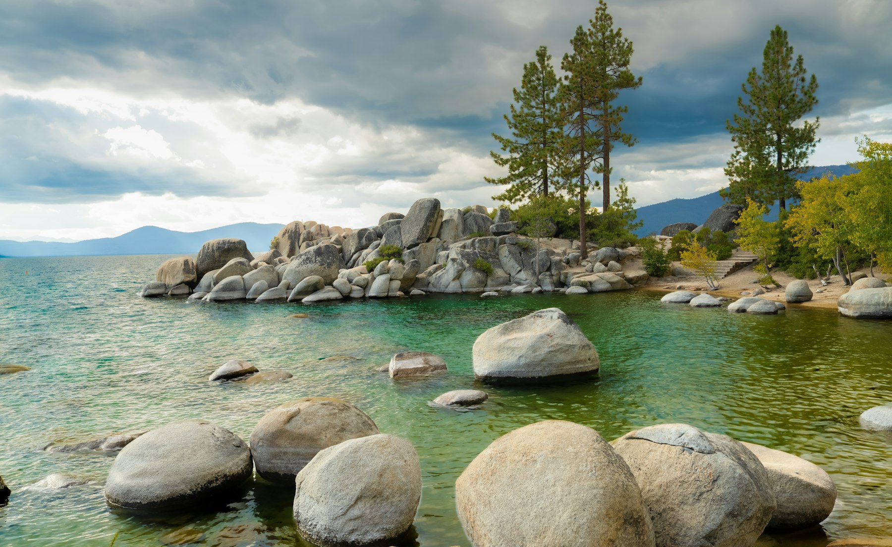 Granite boulders and pine trees along the clear shoreline of Lake Tahoe on the Nevada side