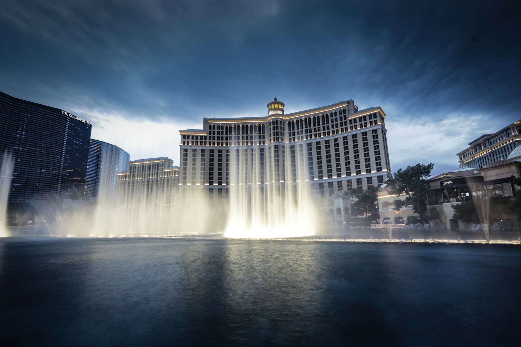 The Fountains of Bellagio shooting water high into the air in front of the hotel at dusk