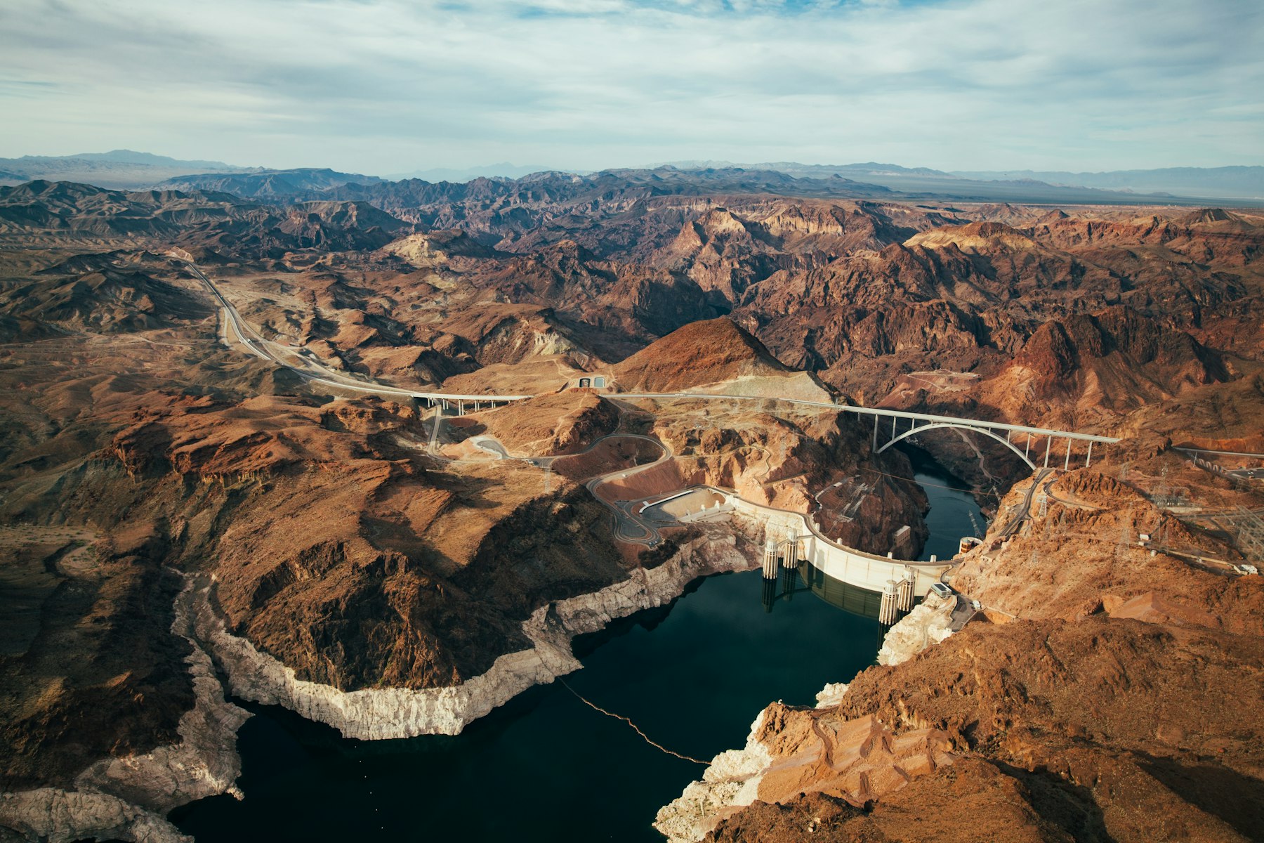 An aerial view of Hoover Dam and the bypass bridge spanning a desert canyon