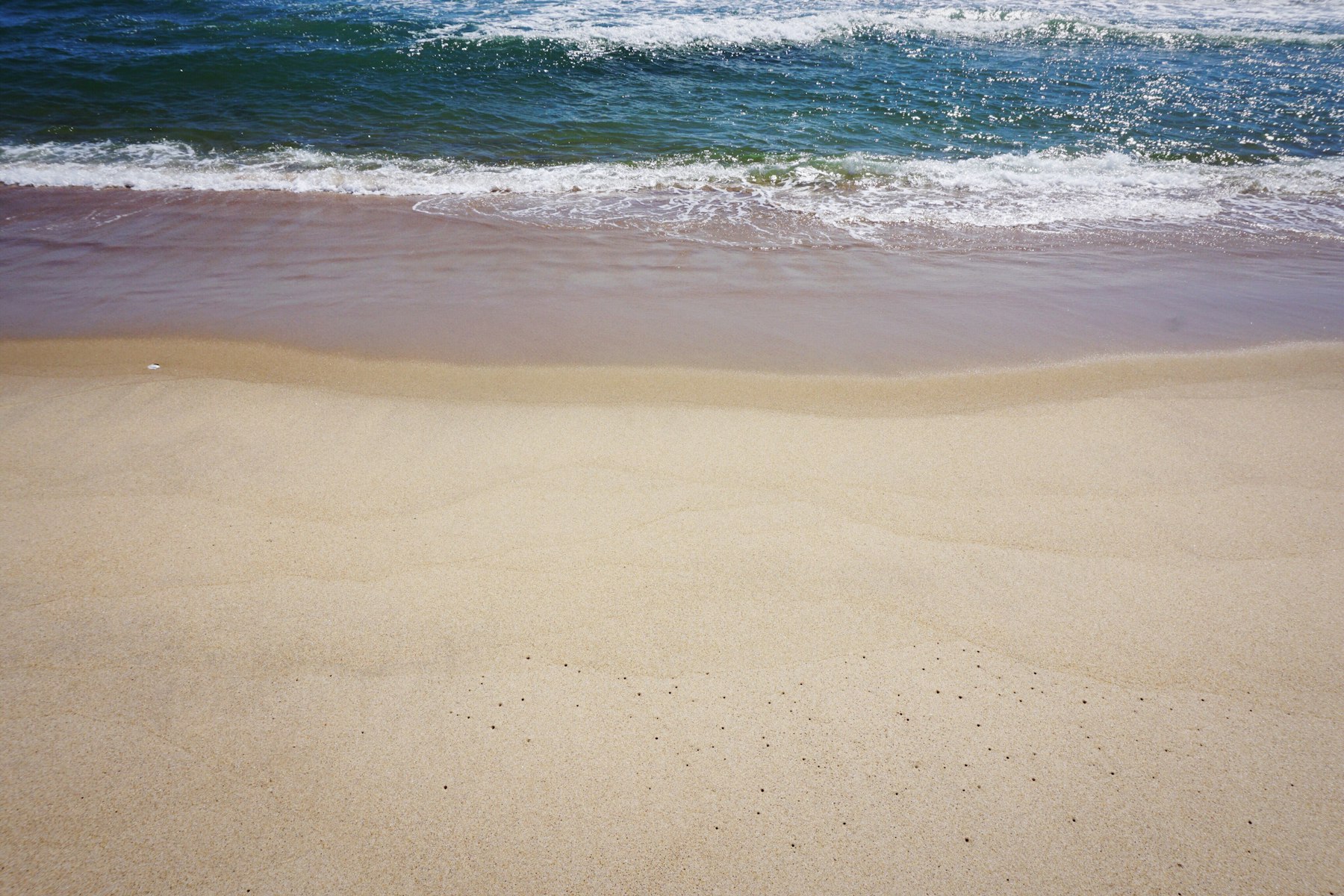 Waves rolling onto a wide empty sand beach on the Atlantic coast