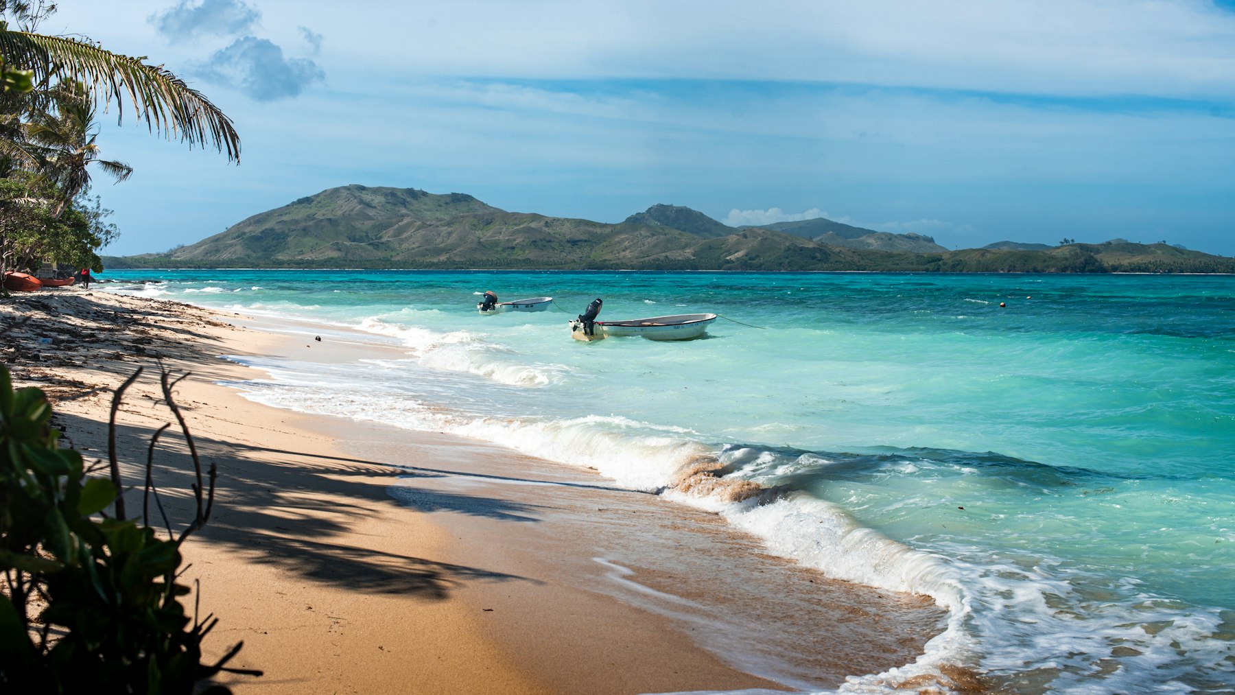 A beach and a boat in the water at Nanuya Island in Fiji