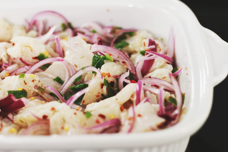 Chopped white fish with red onion and herbs in a white dish