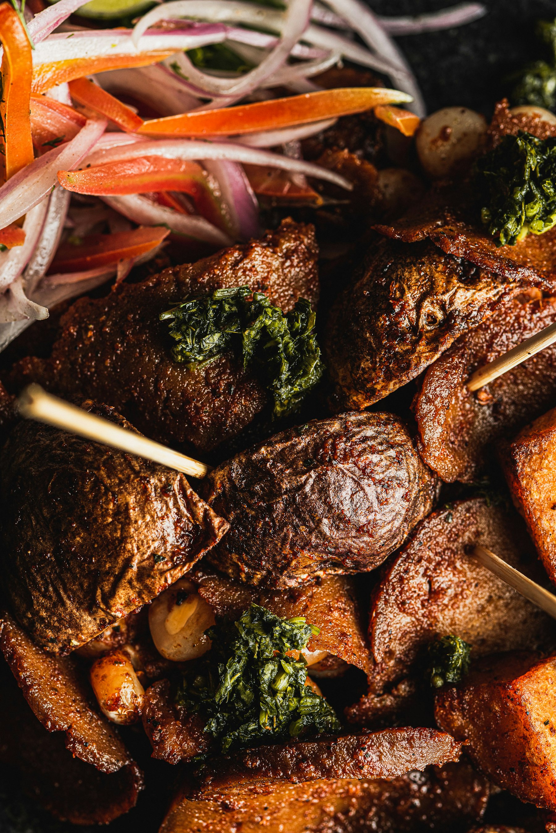 Grilled anticucho skewers of marinated beef heart on wooden sticks
