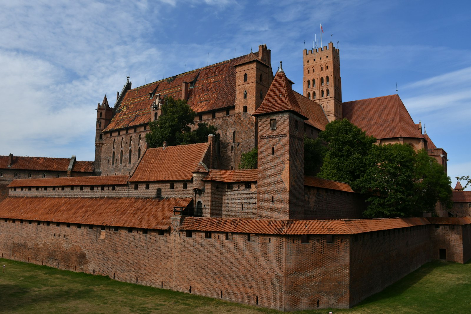 The red brick walls and towers of Malbork Castle above the river