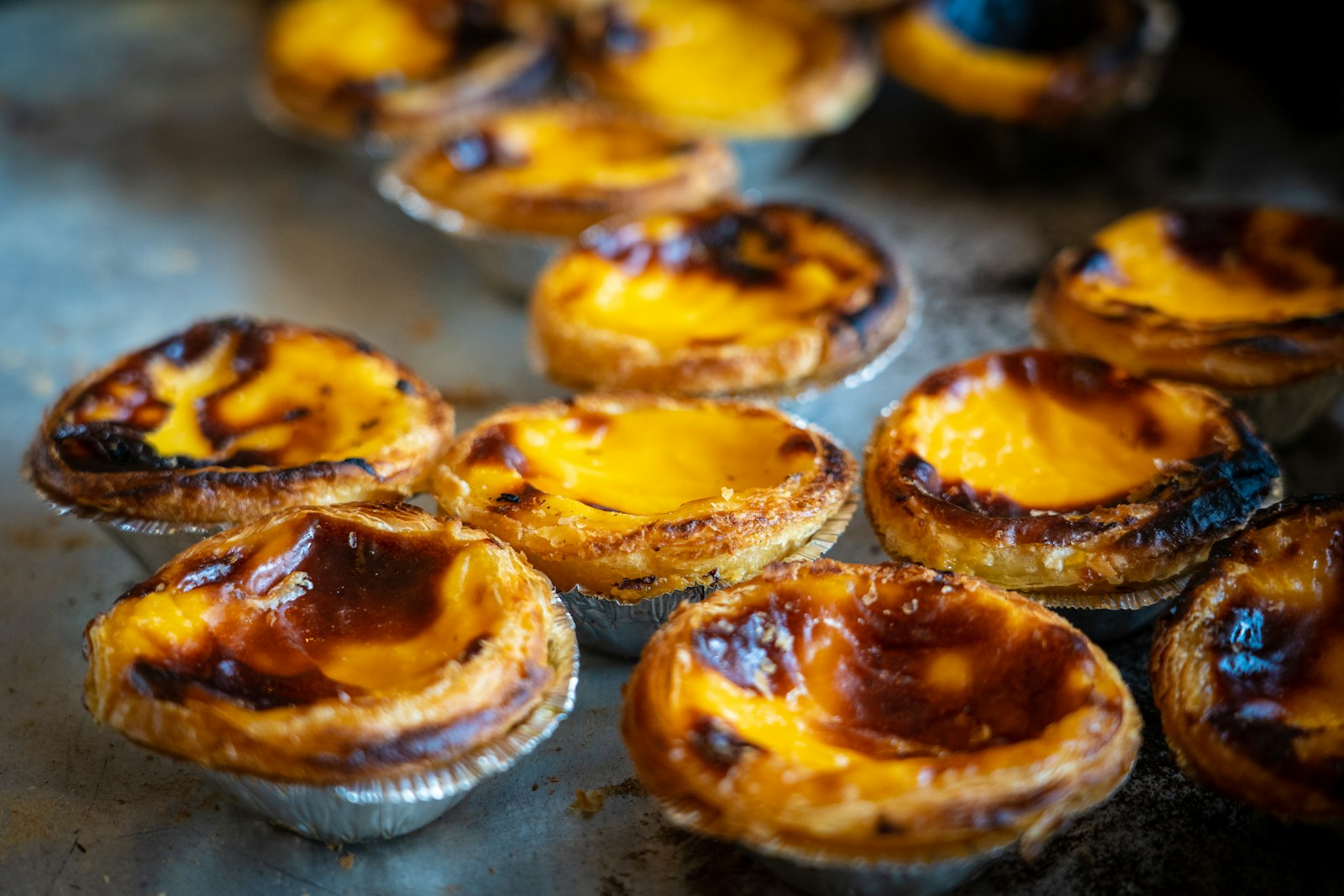 A tray of pastel de nata custard tarts with scorched tops fresh from the oven