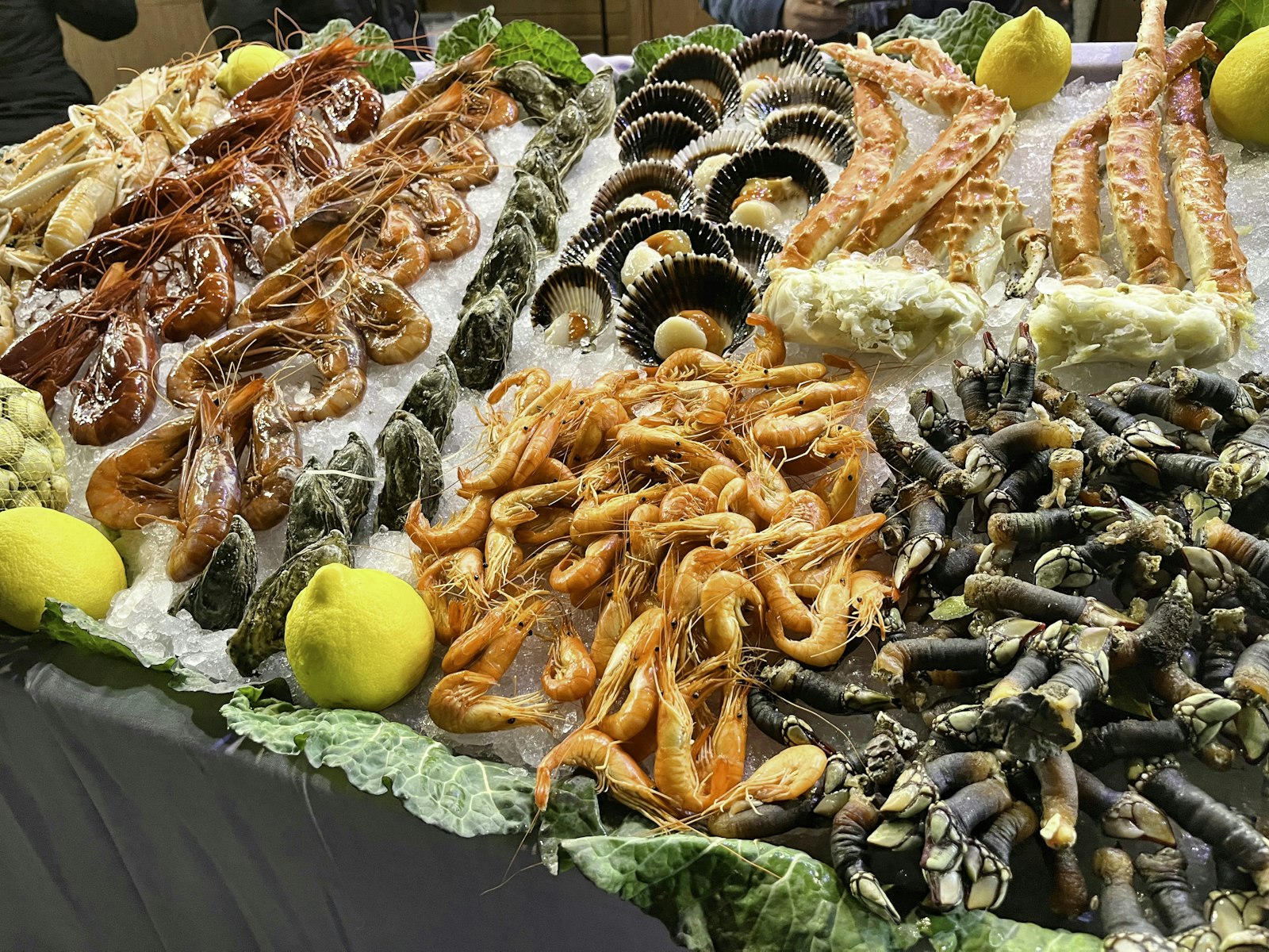 A market counter piled with prawns mussels clams and crab on ice