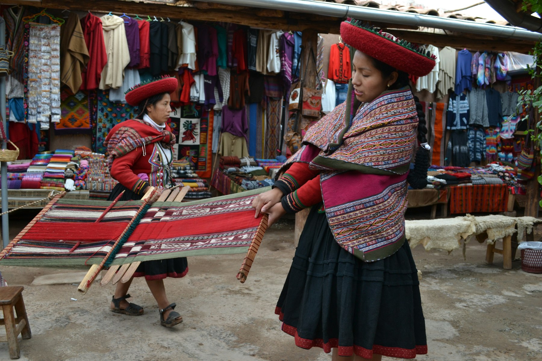 Andean women in traditional dress selling woven textiles at a highland market