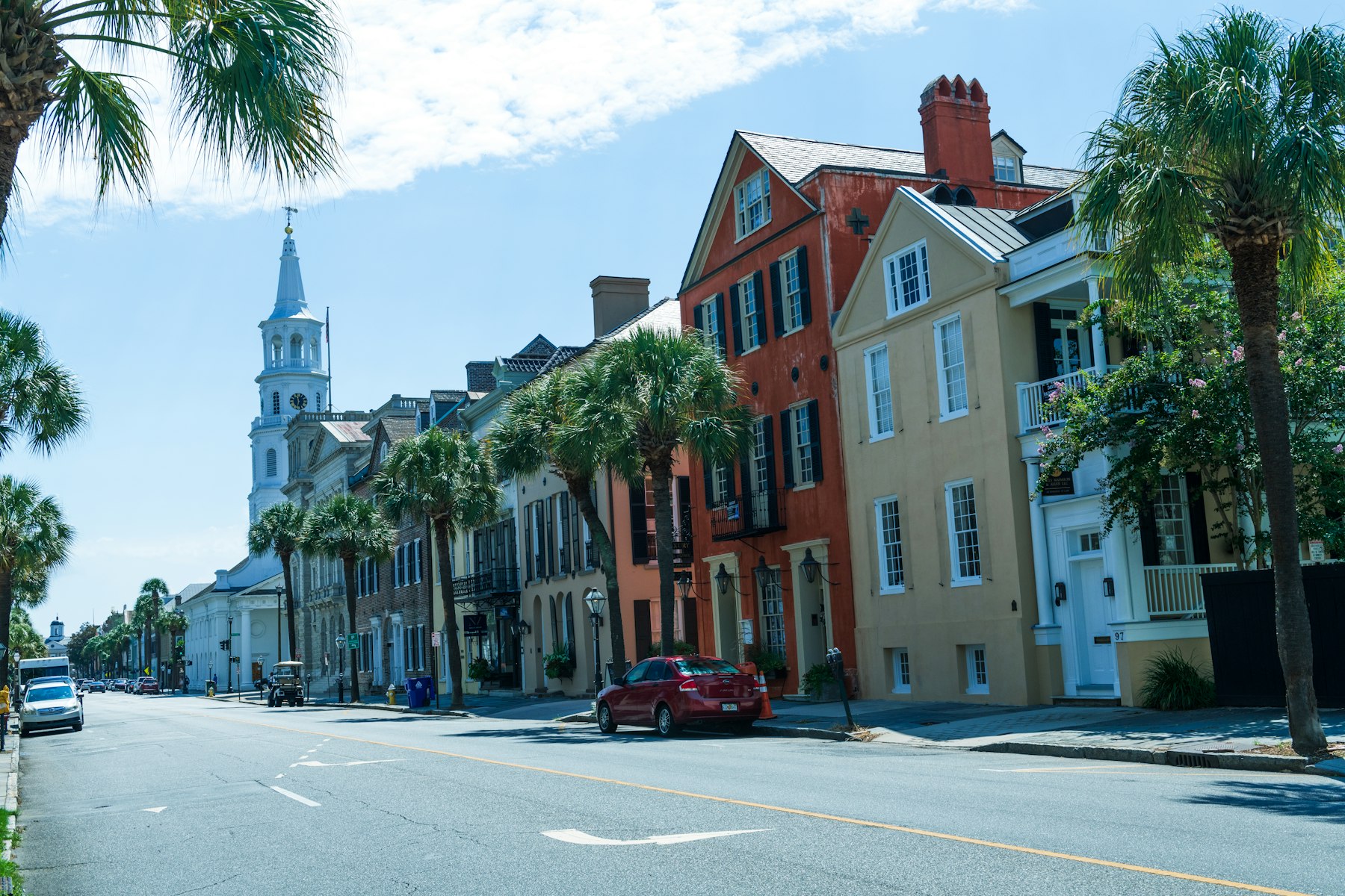 Colourful historic houses and a white church steeple on a street in Charleston South Carolina