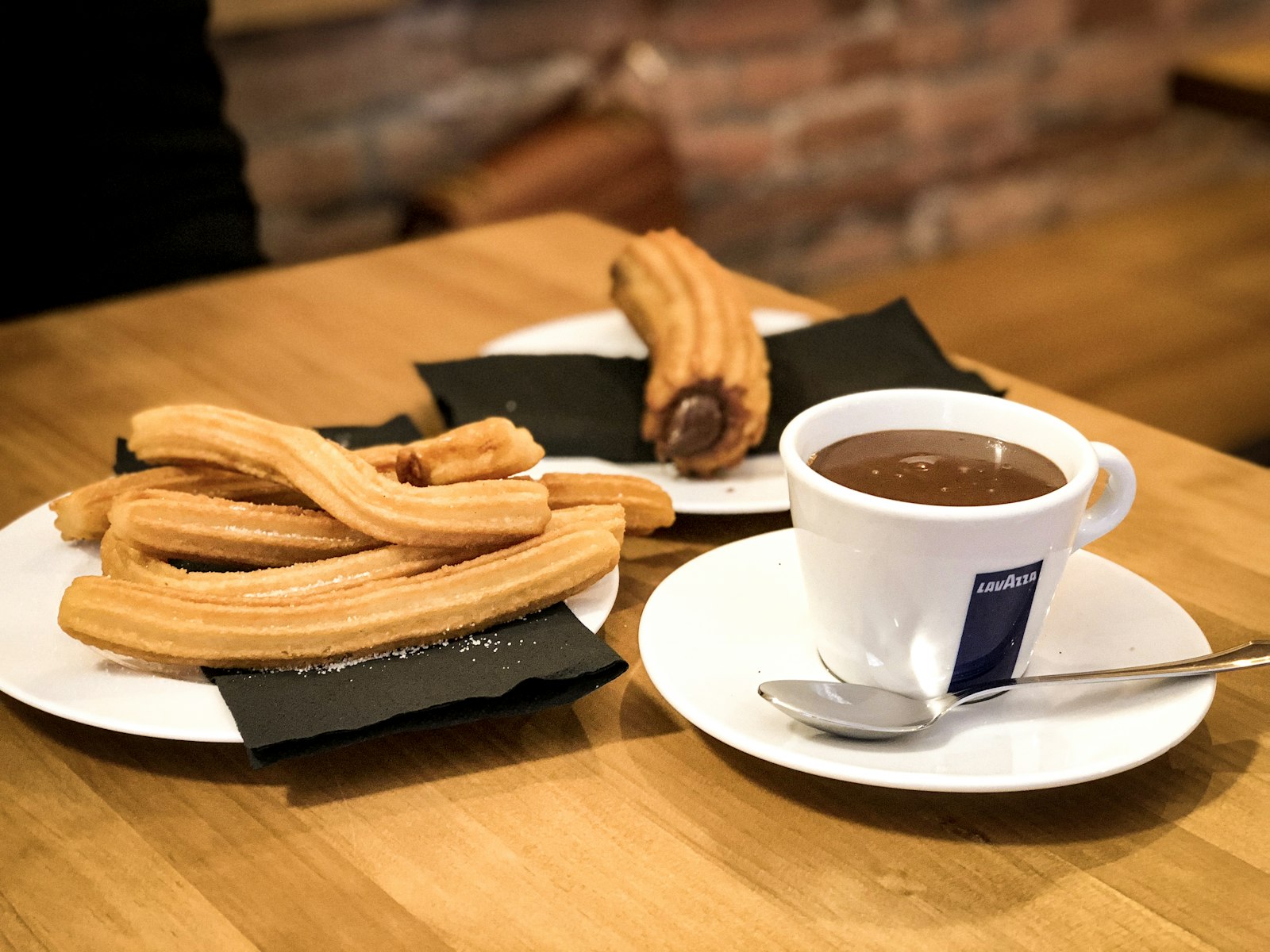Churros on a plate beside a cup of thick hot chocolate