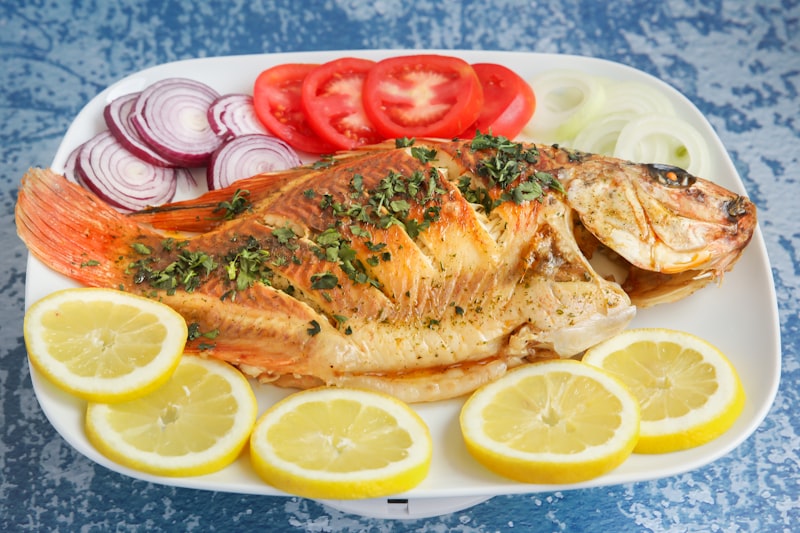 A plate of cooked fish with lemon wedges