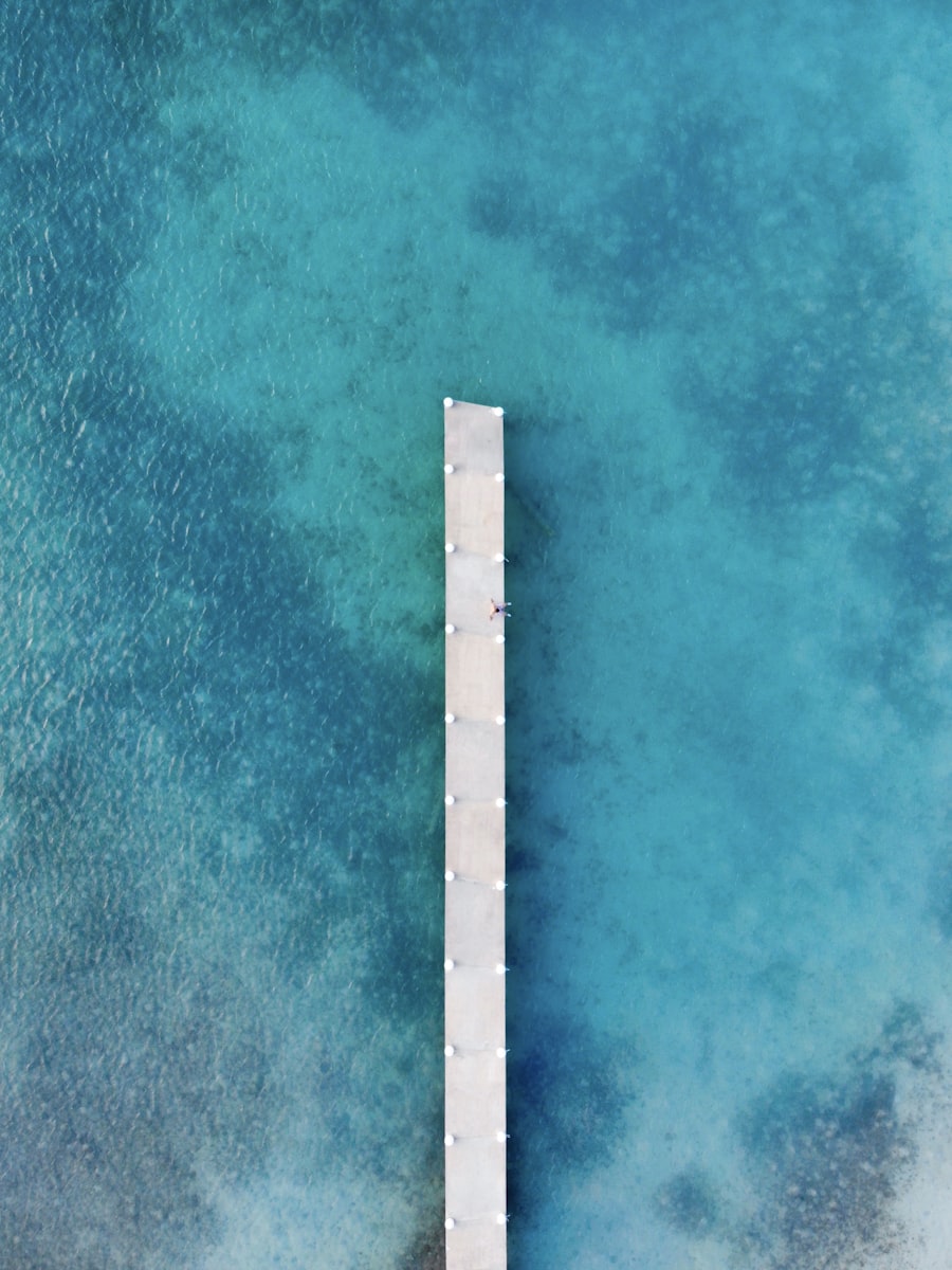 An aerial view of a white dock reaching out over clear turquoise water in the Turks and Caicos Islands