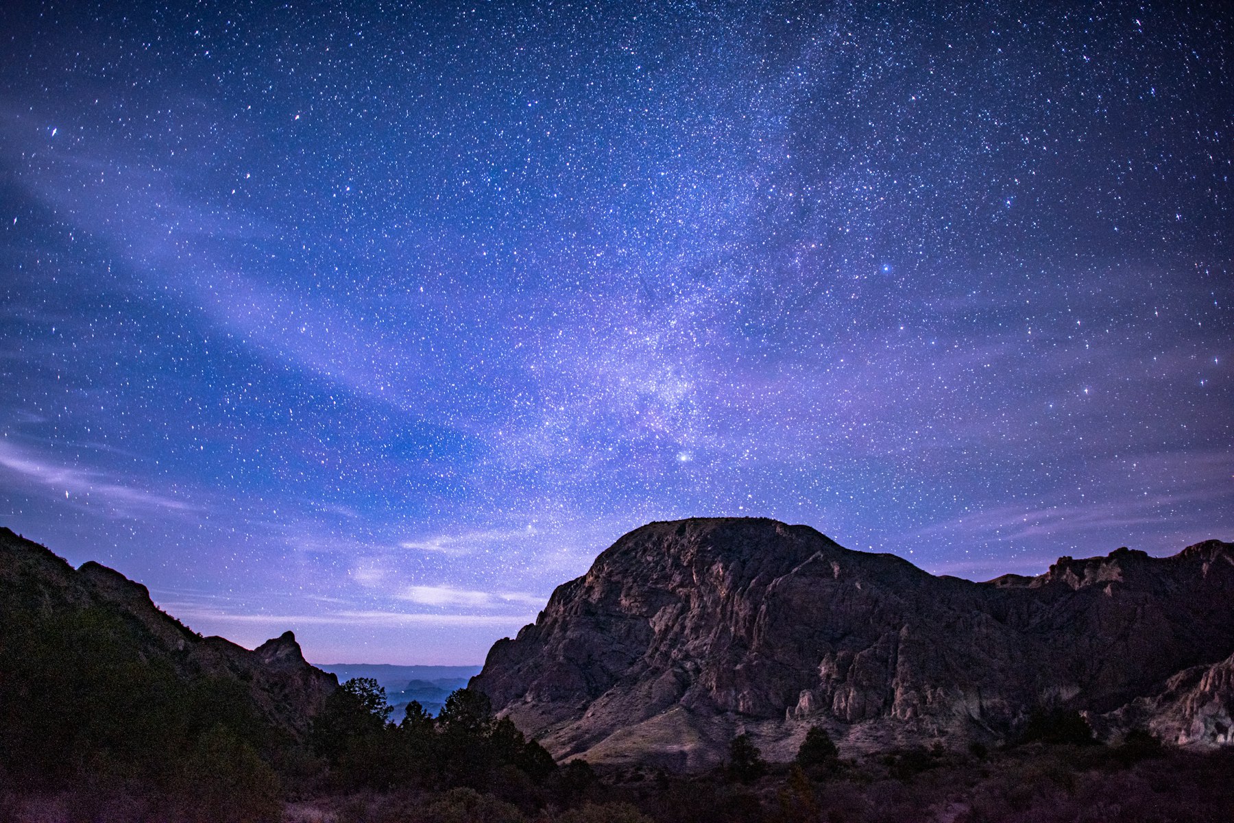 The Milky Way arching over a dark mountain ridge in the west Texas desert