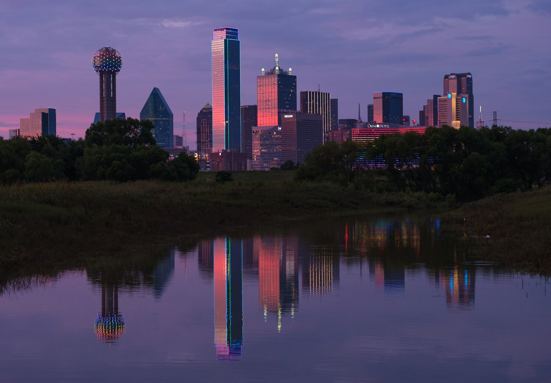 The Dallas Texas skyline with Reunion Tower reflected in still water at dusk