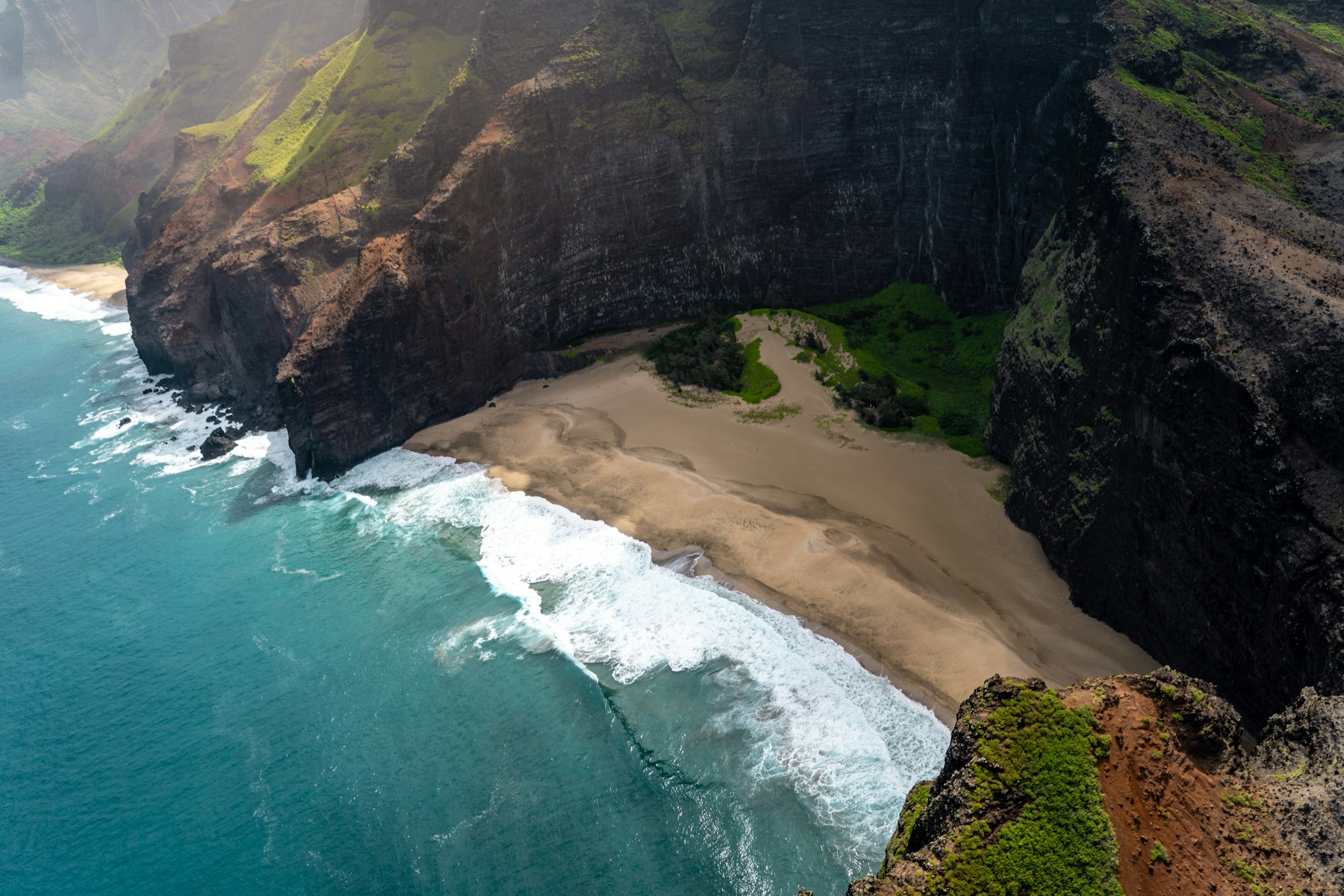 The green ridged cliffs of Kauai in Hawaii meeting the Pacific ocean