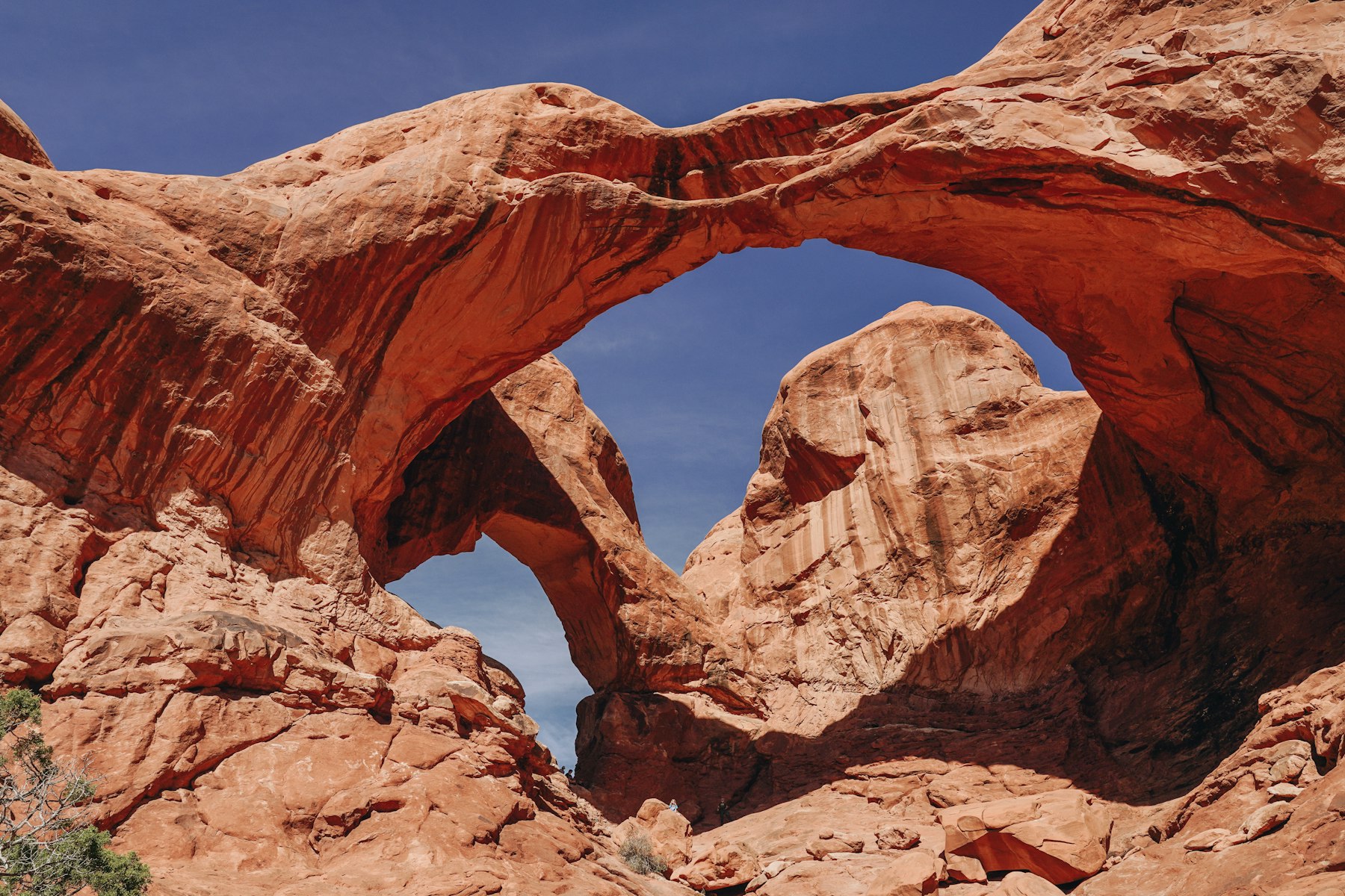 A red rock arch formation in Arches National Park in Utah under a blue sky