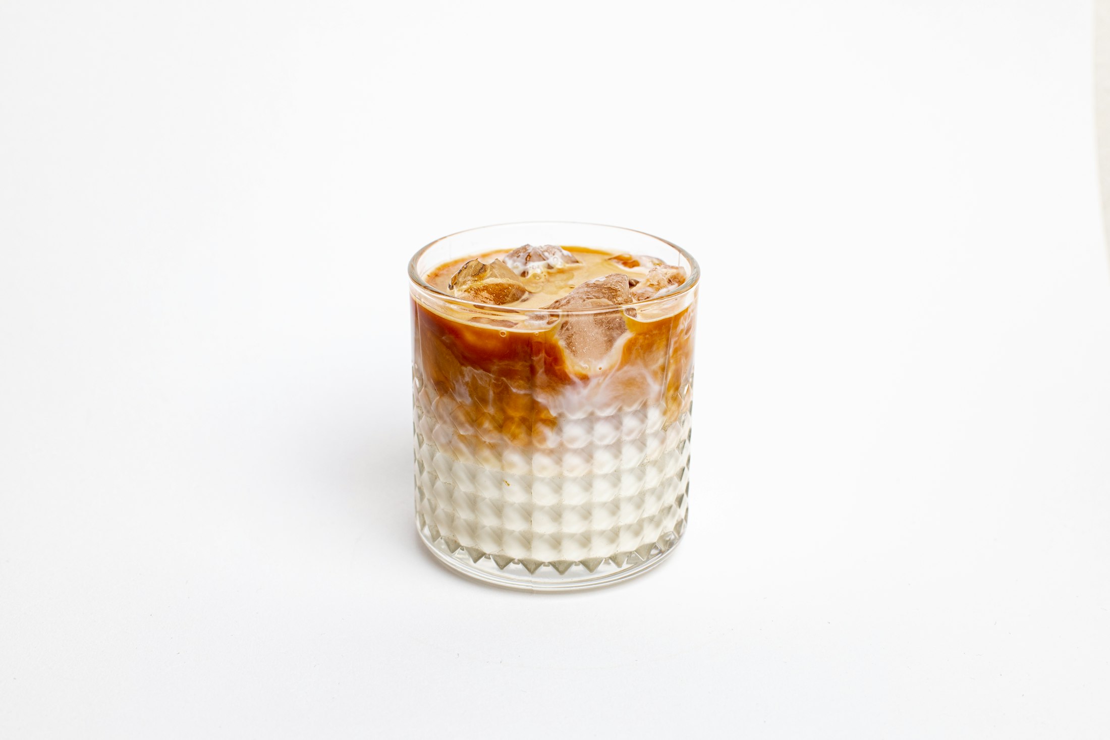 A small glass of Vietnamese iced coffee, dark coffee layered over condensed milk and ice
