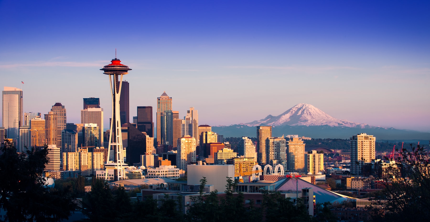 The Space Needle and the Seattle skyline at sunset with Mount Rainier rising behind the city