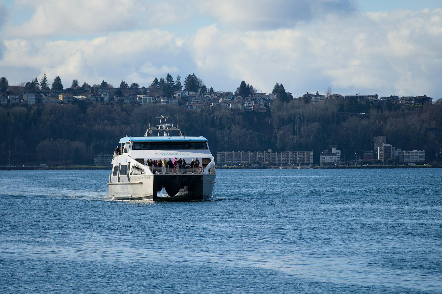 A Washington State ferry crossing open water with forested hills behind it