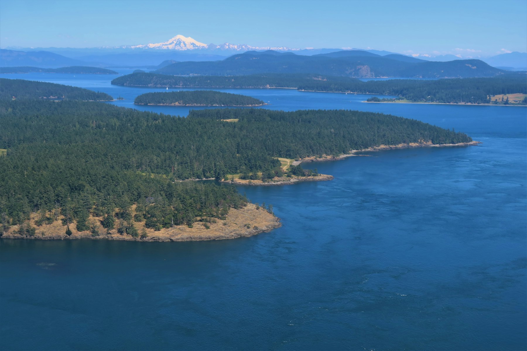 An aerial view of the forested San Juan Islands scattered across blue water