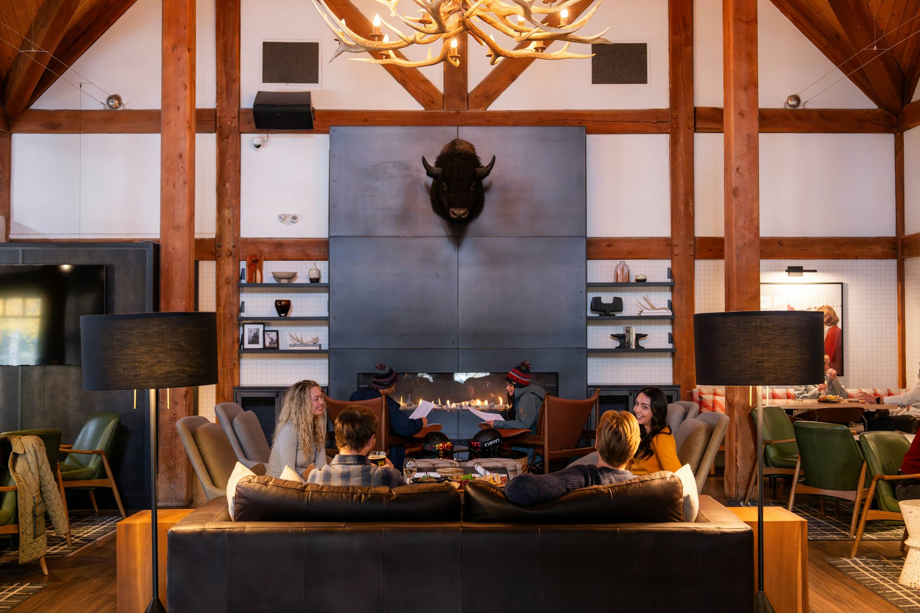 People sitting by a large stone fireplace in a timber national park lodge lounge