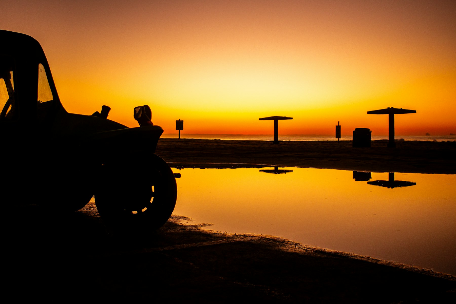 A vintage car silhouetted on a beach at sunrise near Port Elizabeth in the Eastern Cape