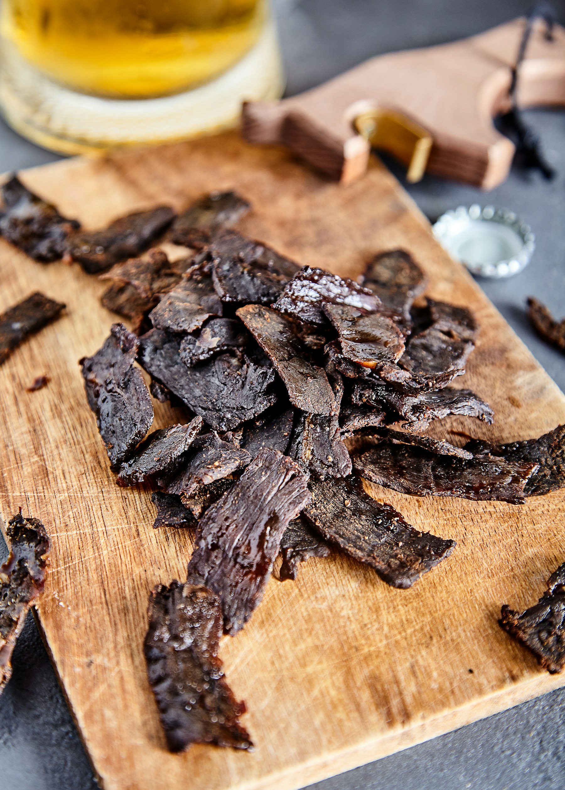 Strips of dried cured meat on a wooden board, South Africans call it biltong