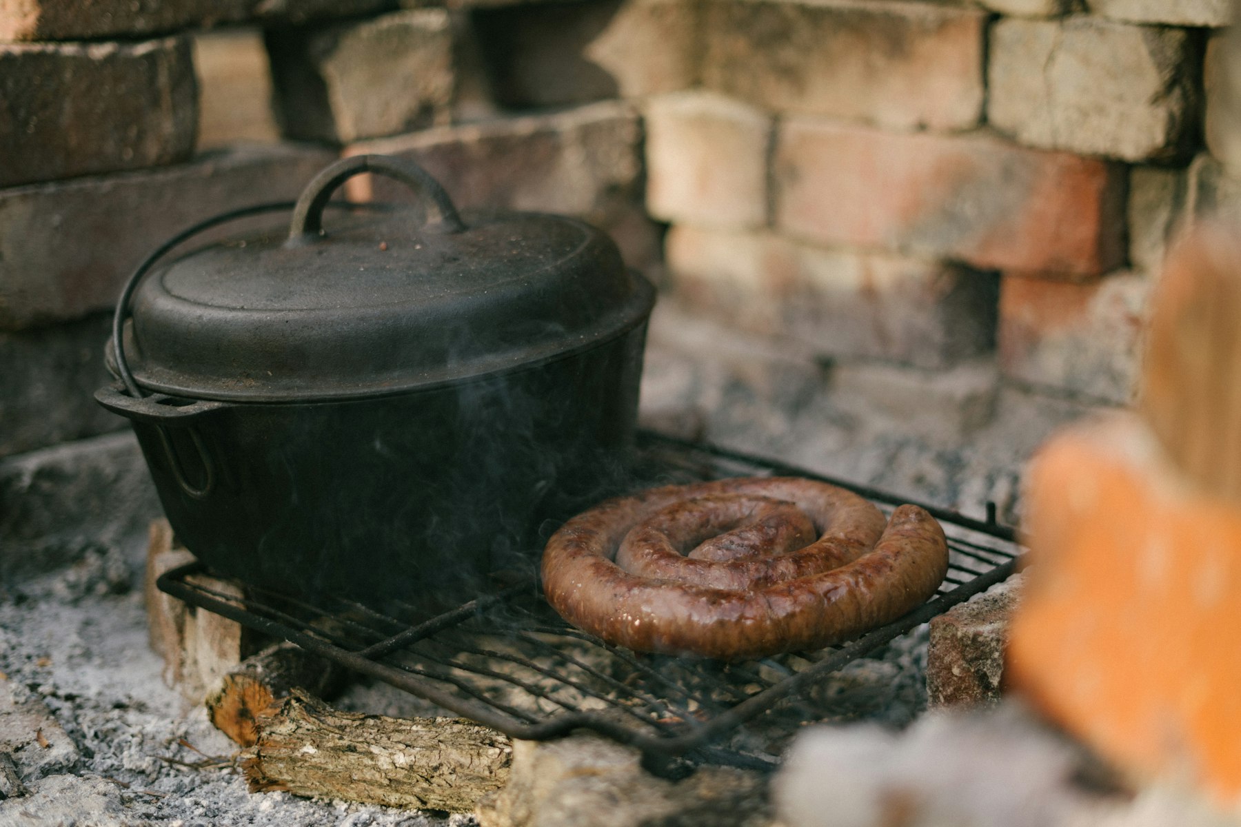 A coil of boerewors sausage cooking over a fire