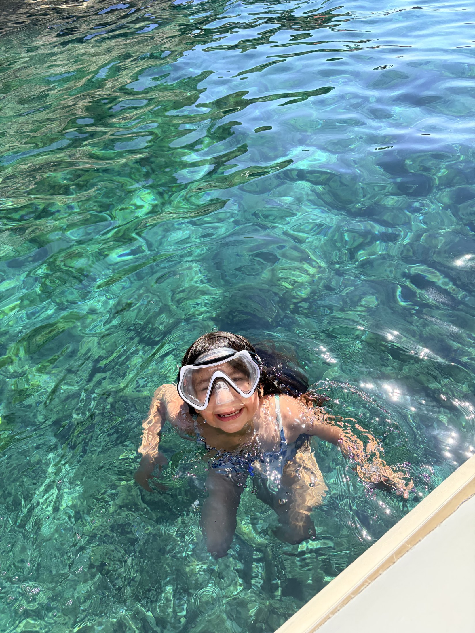 A child in a snorkel mask in clear water